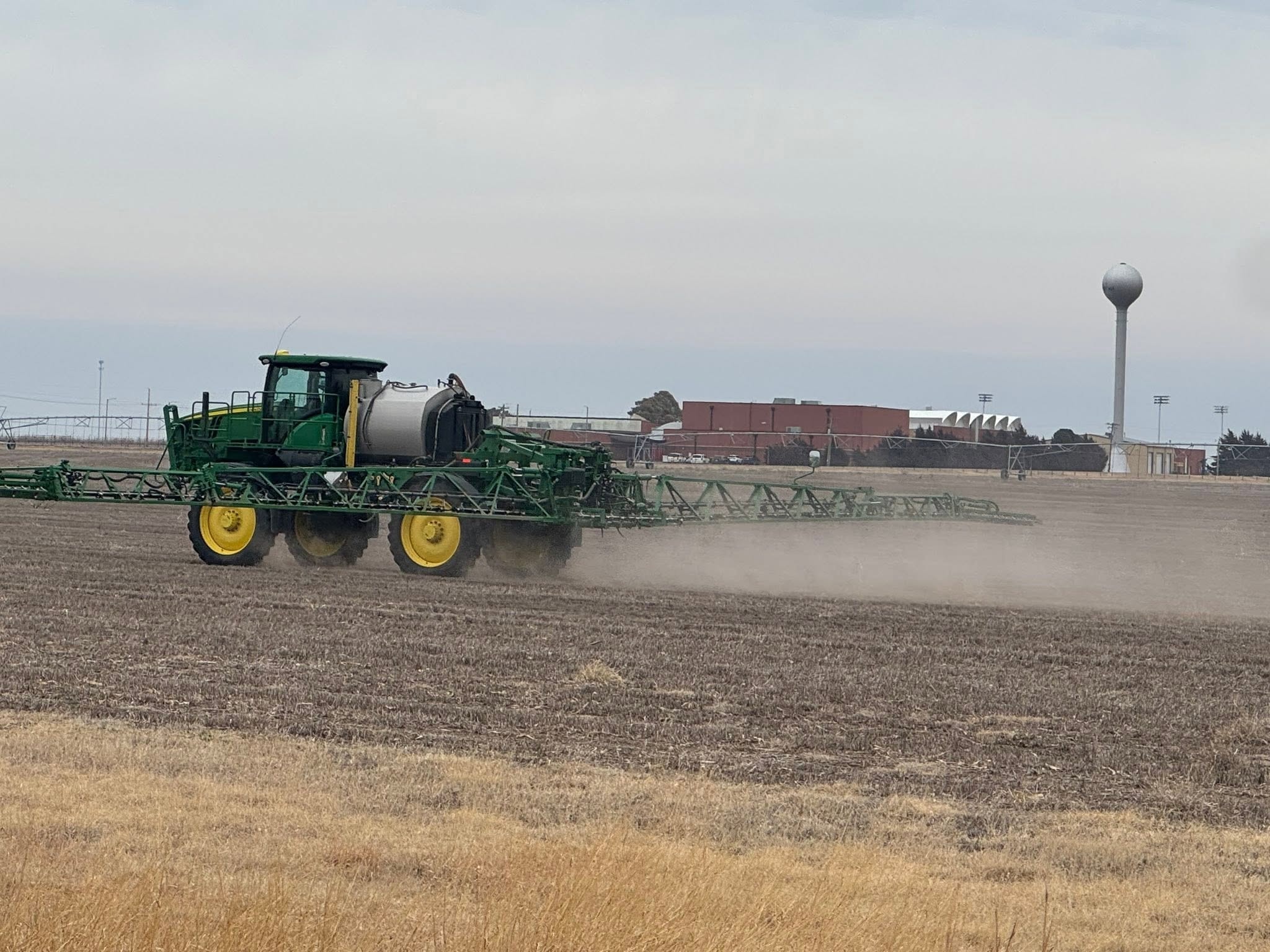Agricultural sprayer applying pesticide in the field