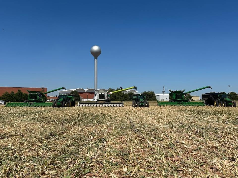 Three combine harvesters lined up in a harvested corn field