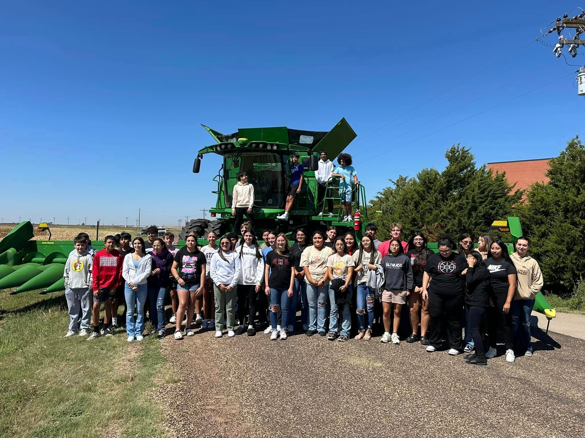 Students posing in front of a John Deere combine harvester