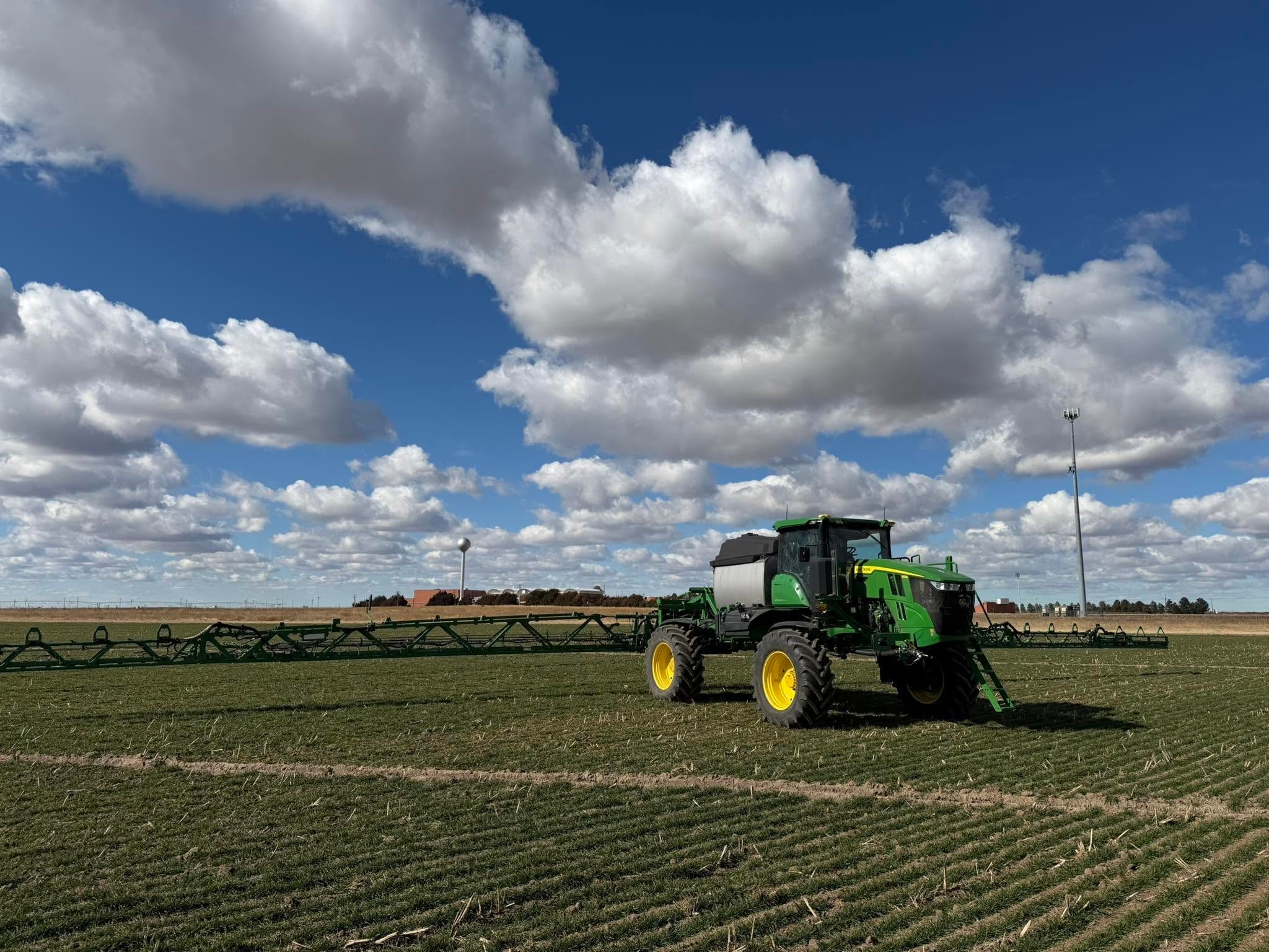 Green tractor spraying crop field