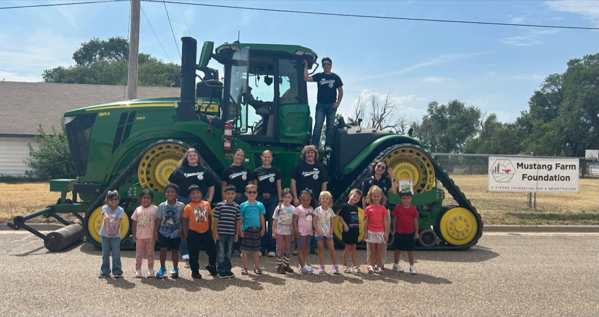 Group posing with a large green tractor