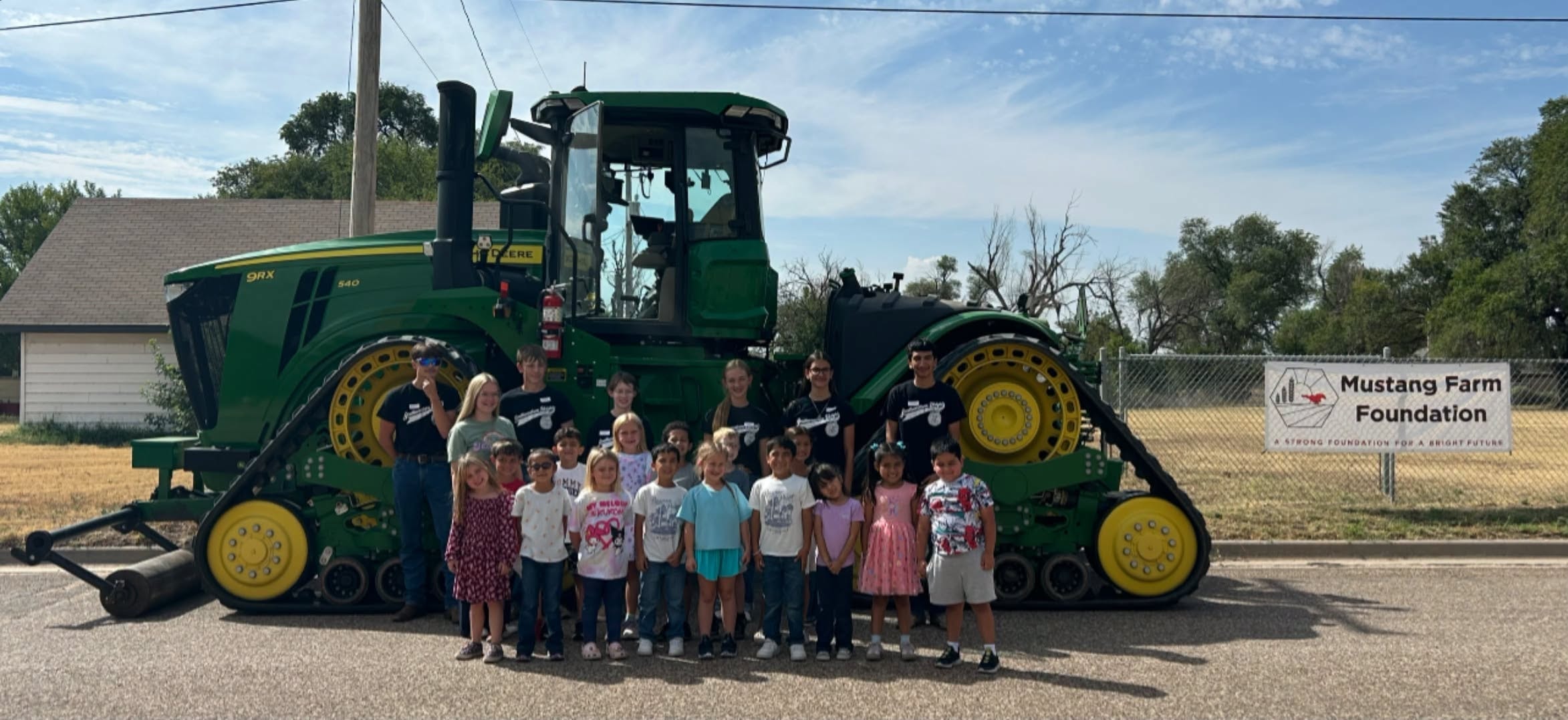 Group posing with the giant green tractor at a foundation event