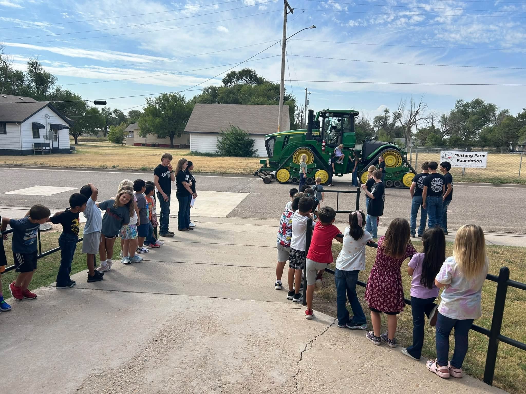 Children gathered around a green farm tractor